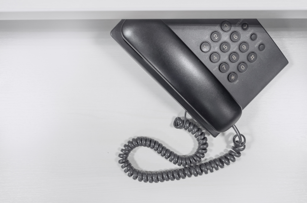Black and white photo of a traditional telephone hanging on a wall, representing fixed line service.